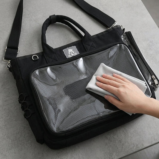 Gentle microfiber cleaning of a black ita bag clear display window on a stable tabletop
