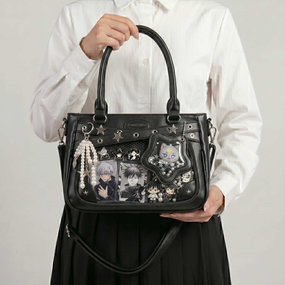 Yume Dual Window Shoulder Ita Bag held by top handles, showing rectangular front display window filled with photocards and pins, and star-shaped side window